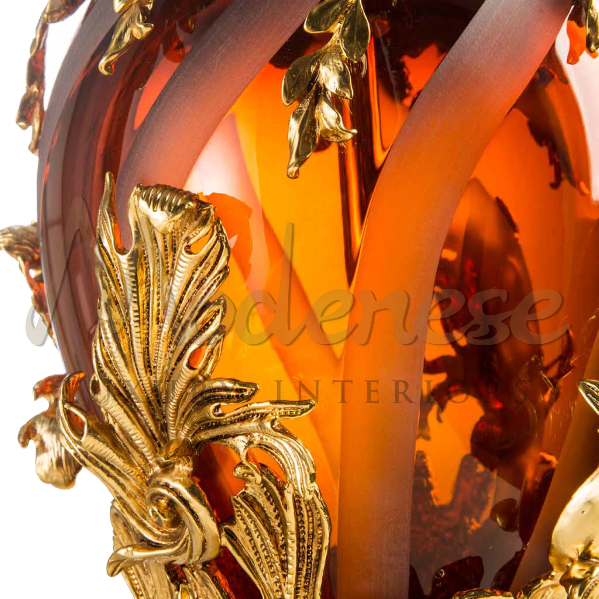 A close-up of an amber crystal glass lamp with intricate gold leaf details