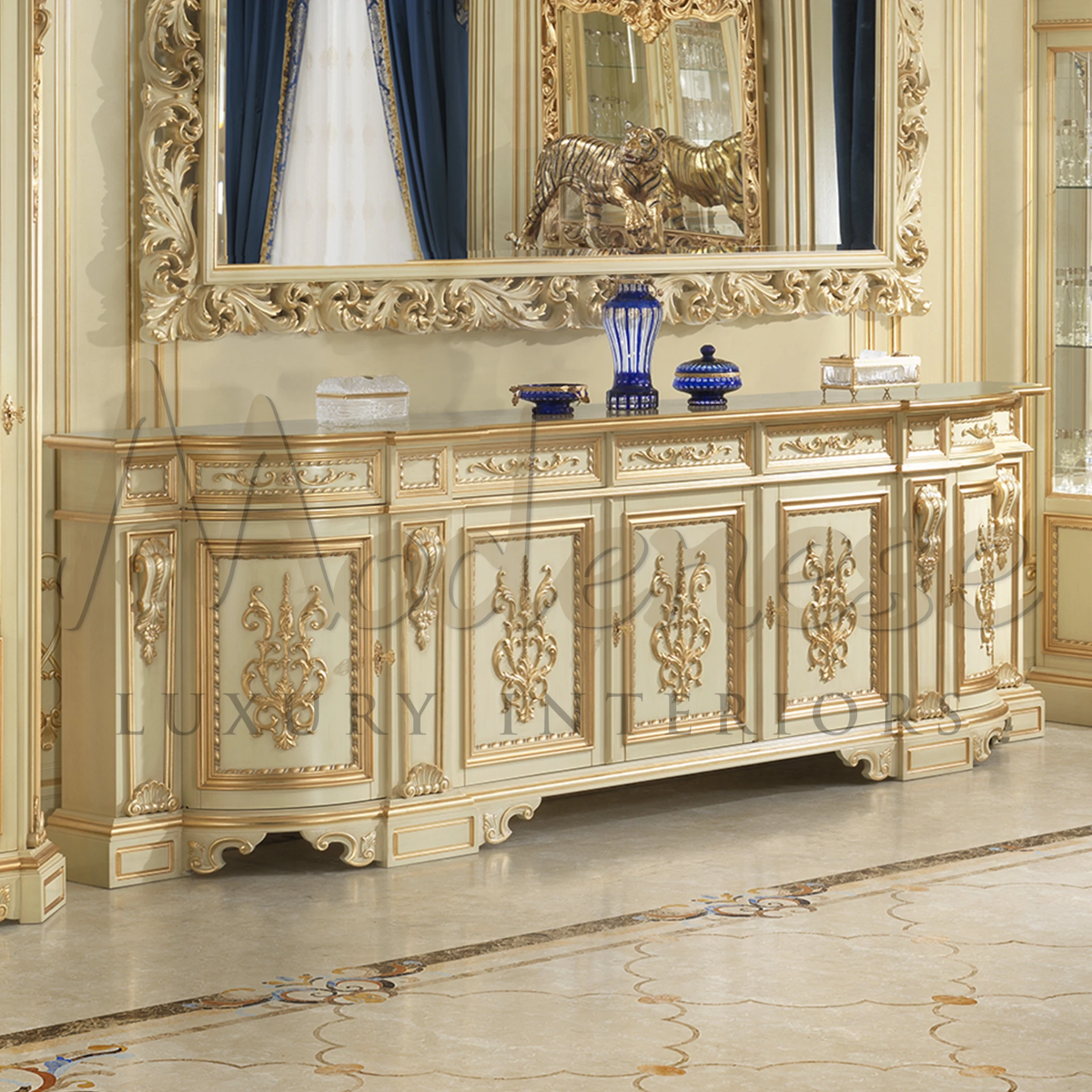 Charming cream coloured sideboard with golden floral carvings, under a mirror with detailed gold frame and luxury decorative items