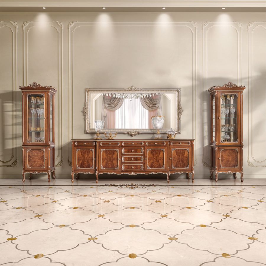 A luxurious soft classic dining room featuring an elegant carved wood table and cream upholstered chairs under a crystal chandelier by Modena Projects.