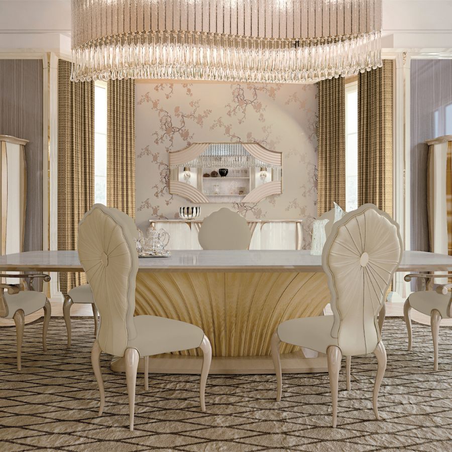 A luxurious eclectic dining room featuring a polished Makassar wood table contrasted with modern grey upholstered chairs under a sculptural crystal chandelier.